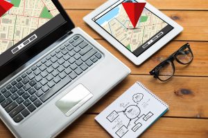 nawigacja, responsywny projekt i koncepcja technologiczna - zbliżenie na laptopie, tablecie, notebooku i okularach z mapą nawigatora gps i schematem na drewnianym stole