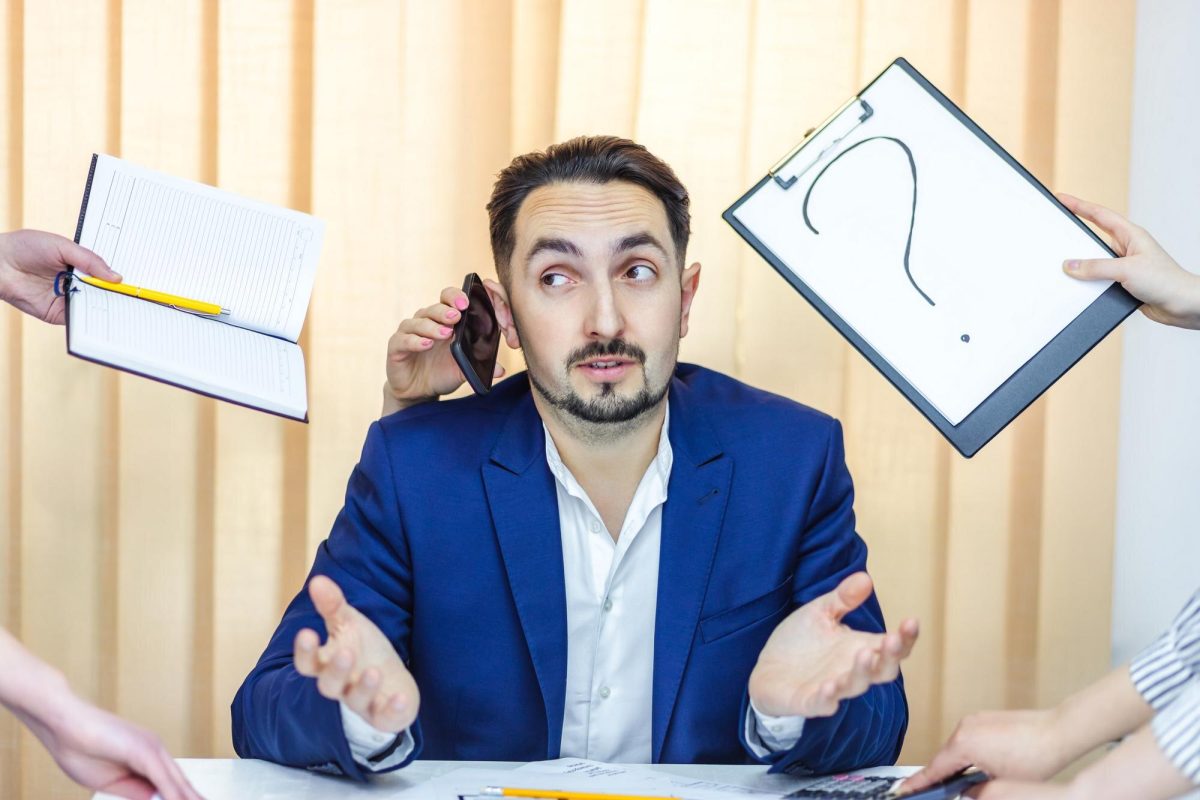 Zdjęcie biznesmena w niebieskim garniturze, kt&oacute;ry ma dużo pracy siedzącej w biurze
