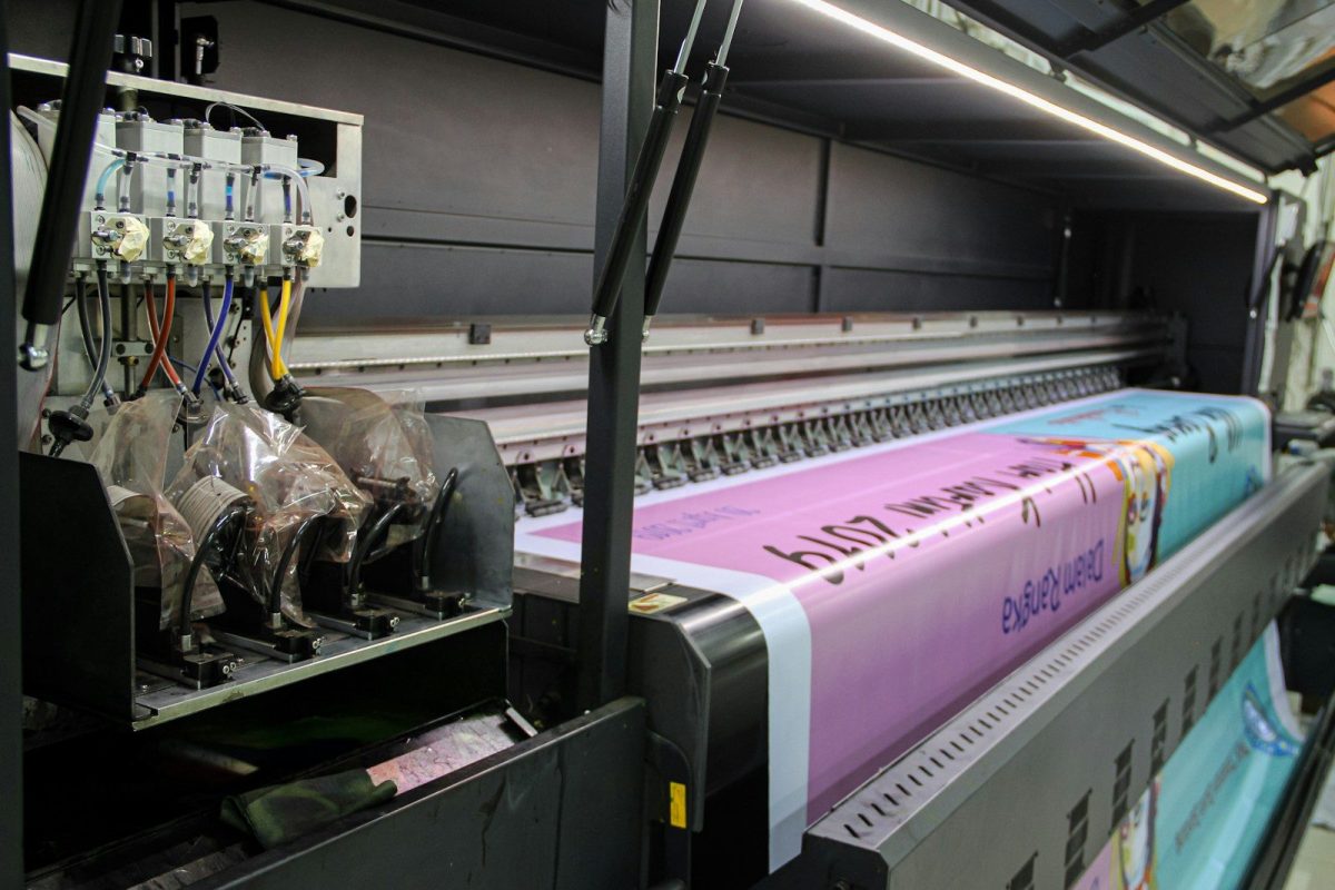 A large industrial printer feeding a long pink banner with printed text